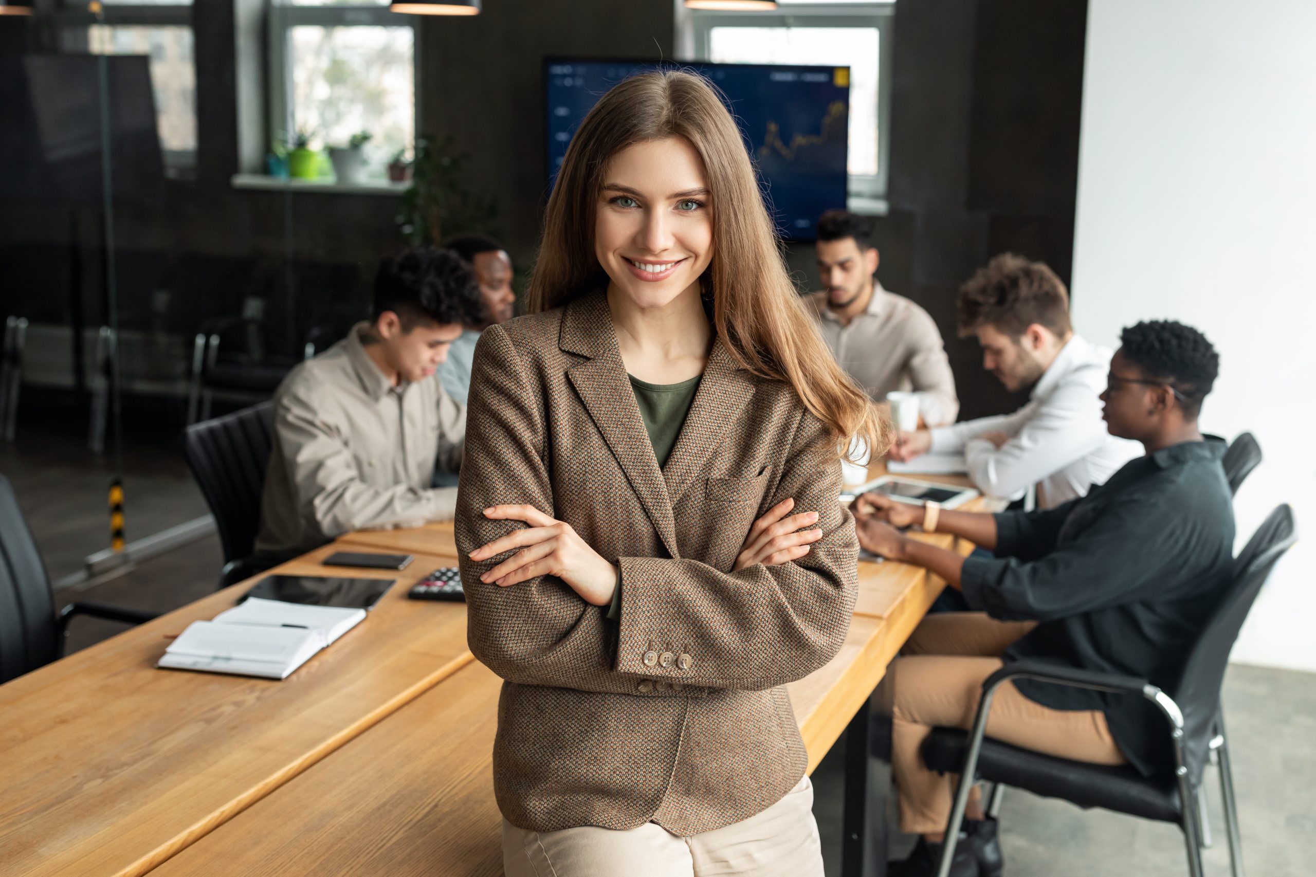 Young businesswoman sitting on desk and posing